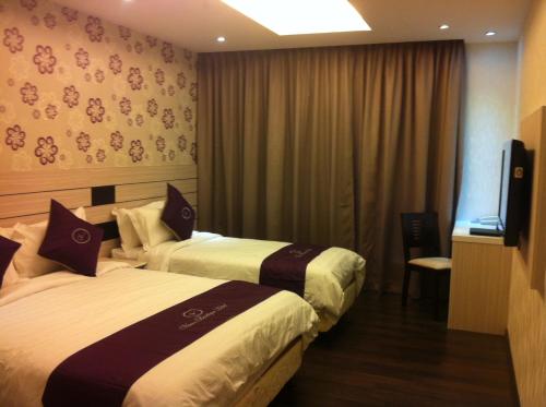 a hotel room with two beds and a flat screen tv at Venus Boutique Hotel in Melaka