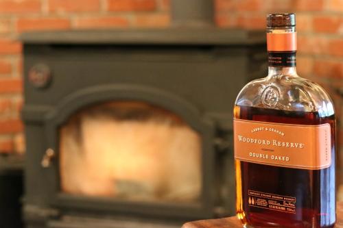 a bottle of whiskey sitting on a table in front of a fireplace at Spa Lodge Redwood Inn in Takayama