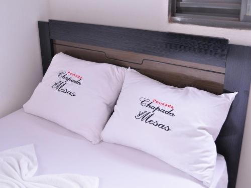 two white pillows on a bed with words on them at Pousada Chapada das Mesas in Riachão
