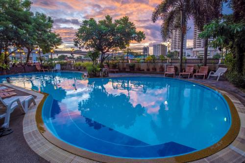 a pool at a hotel with a sunset in the background at New Siam Riverside - SHA Certified in Bangkok