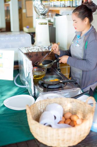 une femme qui cuisine sur un poêle avec un panier de nourriture dans l'établissement Samed Cabana Resort, à Ko Samet