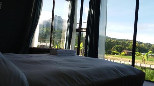 a bedroom with a bed and a large window at Him doy muang pan resort ฮิมดอยเมืองปานรีสอร์ท in Ban Sop Pan
