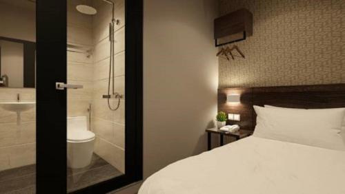 a bedroom with a bed and a bathroom with a shower at The Square Hotel in Skudai