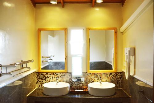 twee wastafels in een badkamer met twee spiegels bij Cocoville in Pasikuda