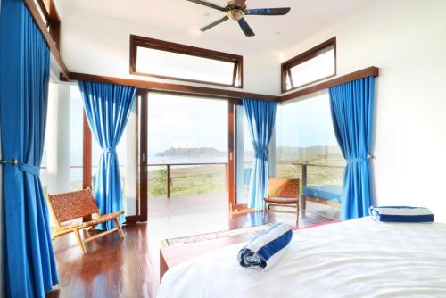 a bedroom with a bed with blue drapes at Villa Nambung in Selong Belanak