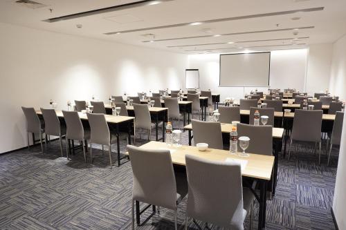 a conference room with tables and chairs and a screen at Midtown Residence Surabaya in Surabaya