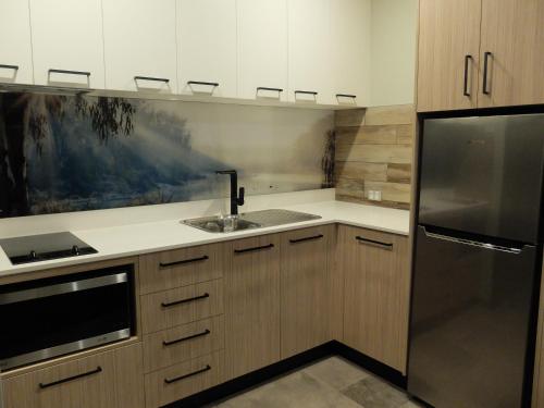 a kitchen with a sink and a refrigerator at Barooga River Gums Motor Inn in Barooga