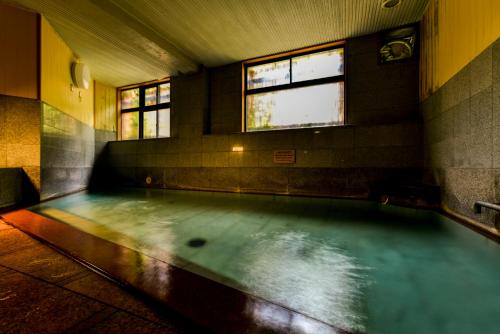 een zwembad met water in een kamer met 2 ramen bij Takamiya Ryokan Yamakawa in Yonezawa