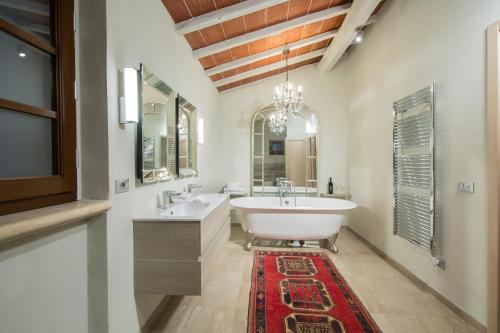 a bathroom with a tub and two sinks and a rug at Borgo Argiano in Castelnuovo Berardenga