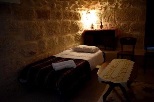 a bedroom with a bed and a chair in a brick wall at Hosh Al Subbar in Bethlehem