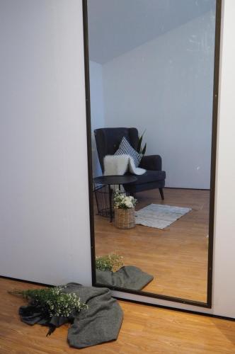 a mirror reflecting a living room with a couch and a chair at La Malila Hostel in Udon Thani