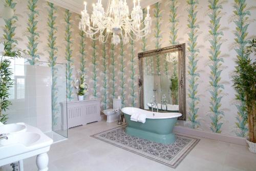 een badkamer met een kroonluchter, een bad en een spiegel bij Rockhill House in Letterkenny