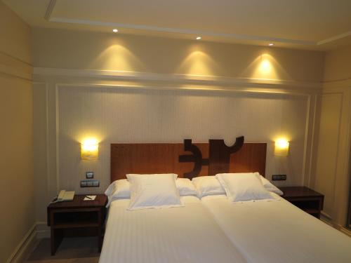 a large white bed in a room with two lamps at Hotel Olid in Valladolid