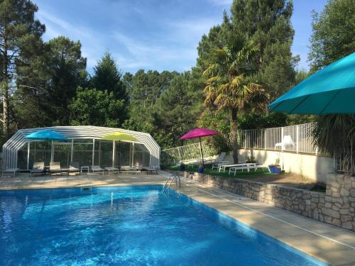 einen Pool mit einem Zelt und einem Sonnenschirm in der Unterkunft Village de gîtes Ravel in Saint-Jean-du-Gard