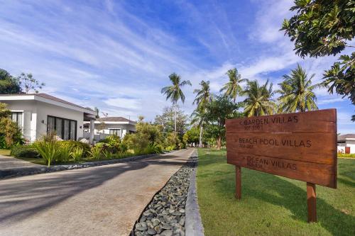 a sign in the grass next to a street at Kandaya Resort in Daanbantayan