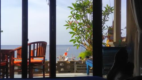 a view of the ocean from a room with two chairs at Tambun Sari Beach Homestay in Amed