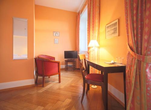 a room with a desk and a table with chairs at hotel brasserie au violon in Basel