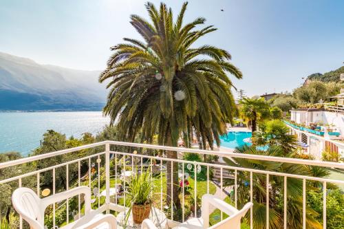 uma varanda com uma palmeira e vista para a água em Hotel Riviera Panoramic Green Resort em Limone sul Garda