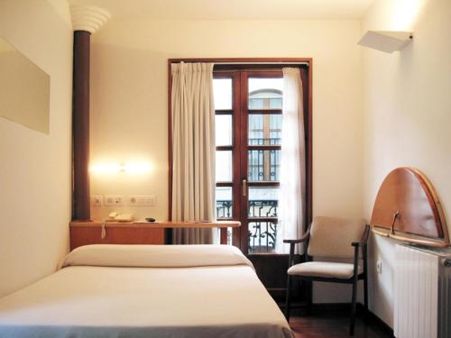 a bedroom with a bed and a chair and a window at La Plaza I in Luanco