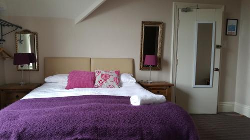a bedroom with a bed with a purple blanket and mirrors at Moorgarth Guesthouse in York