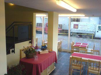 a restaurant with two tables and a television in a room at Eckotel H1 in Eckernförde