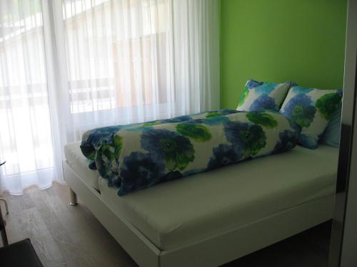 Bett in einem Zimmer mit grünen Wänden und Fenstern in der Unterkunft Casa Irmella 16 in Arosa