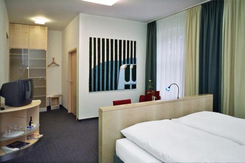una camera d'albergo con letto e TV di Hôtel Galerie a Greifswald