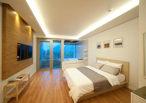 a bedroom with a large bed and a large window at Comma&Spa Resort in Seogwipo