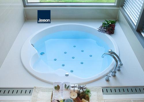 a large bath tub in a bathroom with a window at Comma&Spa Resort in Seogwipo