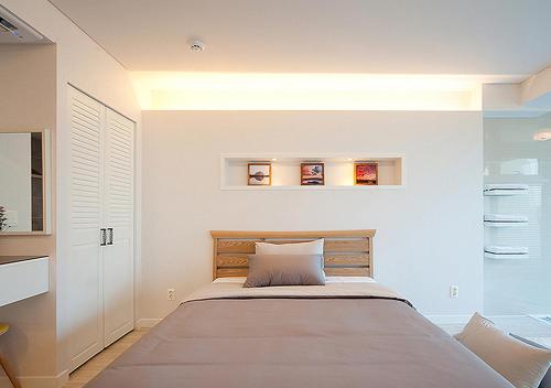 a bedroom with a large bed with white walls at Comma&Spa Resort in Seogwipo