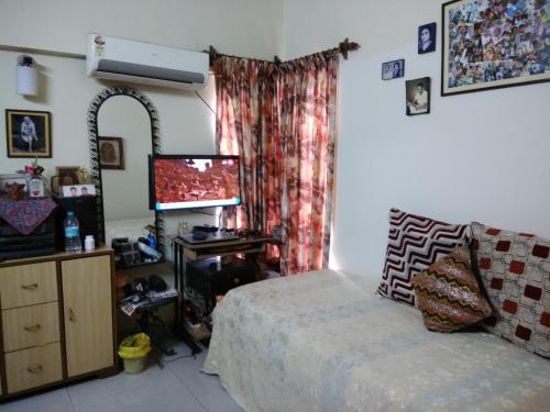 1 dormitorio con cama, espejo y TV en Joy's Nest, en Calcuta