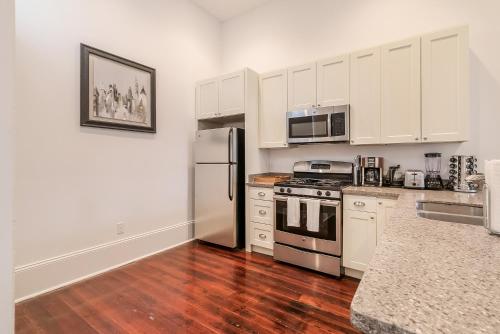 a kitchen with white cabinets and a stainless steel refrigerator at Spacious 2BR in Prime Garden District Location w Pool in New Orleans