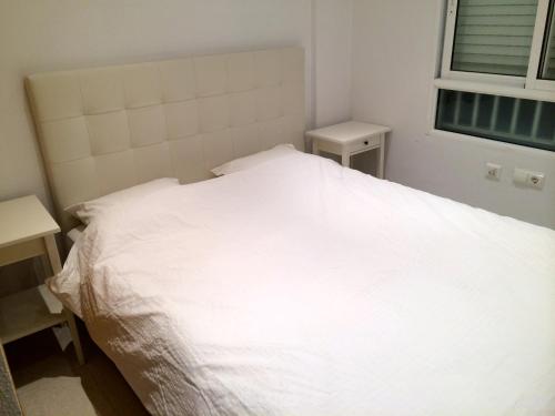 - un lit blanc dans une chambre avec fenêtre dans l'établissement Beach Front Ground Floor Flat Playa San Juan, à El Campello