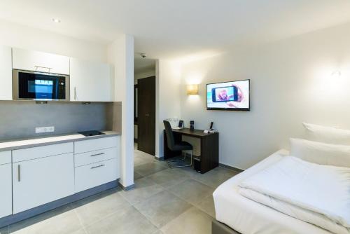 a bedroom with a bed and a desk with a sink at DuDa Boarding Apartments in Langenbruck
