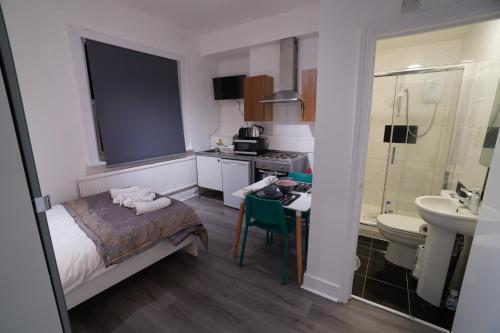 ロンドンにあるLondon Queen Park Apartmentsのベッド1台とバスルームが備わる小さな客室です。