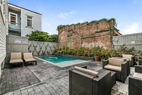 a backyard with a pool and chairs and a brick wall at Spacious 2BR in Prime Garden District Location w Pool in New Orleans