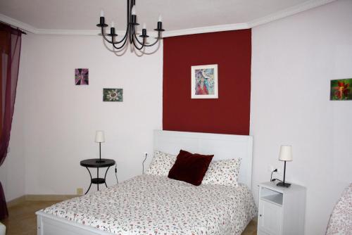 Un dormitorio con una cama con una pared de acento rojo en El Rincón del Violinista, en Cuenca