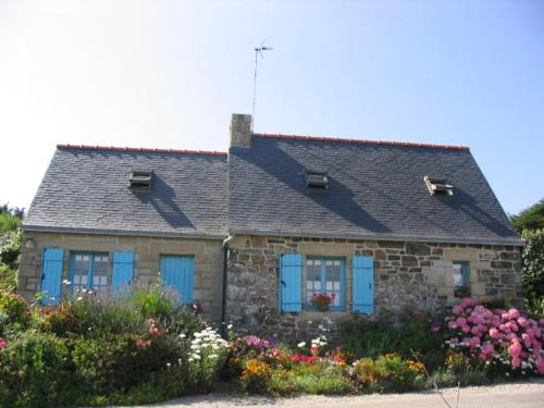 une maison en pierre avec des fenêtres bleues et des fleurs dans l'établissement lemoign-locations, à Crozon