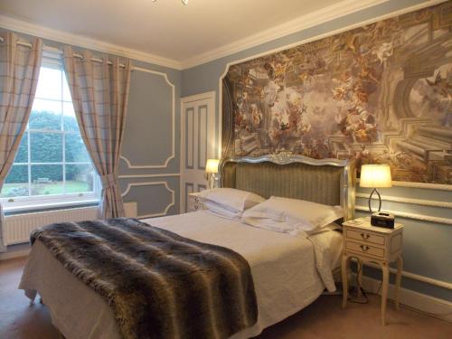 a bedroom with a bed with a large painting on the wall at Rectory Manor in Lavenham