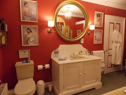 a bathroom with a sink and a toilet and a mirror at Rectory Manor in Lavenham