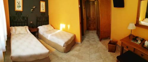 a room with two beds in a room with yellow walls at Posada Del Camino Real in Torrelaguna