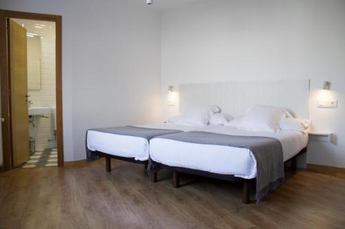 サンティアゴ・デ・コンポステーラにあるA Casa do Pexigoのベッドルーム1室(白いシーツが備わるベッド2台付)
