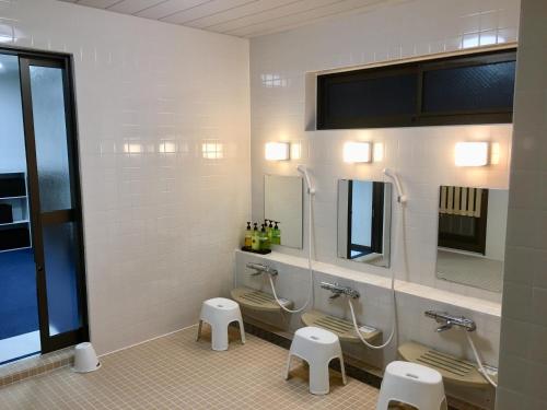 a bathroom with three urinals and two sinks and mirrors at Hotel Tetora Hachinohe in Hachinohe