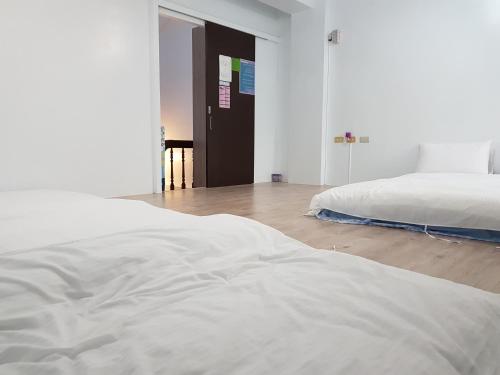a white bedroom with a bed and a wooden floor at Fire B&B in Chishang