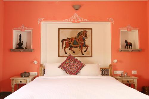 a bedroom with an orange wall with a bed and two mirrors at Little Garden Guest House in Udaipur