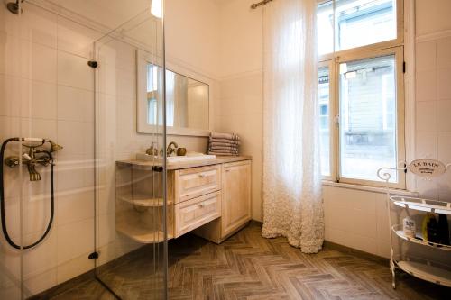 W łazience znajduje się prysznic, umywalka i lustro. w obiekcie Modern History Apartment w Tallinnie