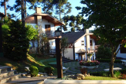 a white house with a porch and stairs to it at Pousada Recanto dos Sonhos in Campos do Jordão