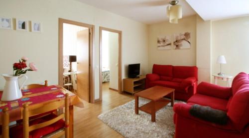 a living room with two red couches and a table at Apartamentos Turísticos Real Valle Ezcaray in Zorraquín