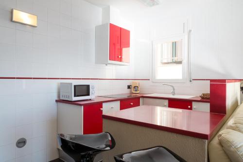 パラフルジェイにあるLes Formigues 3のキッチン(赤と白のキャビネット、黒の椅子付)