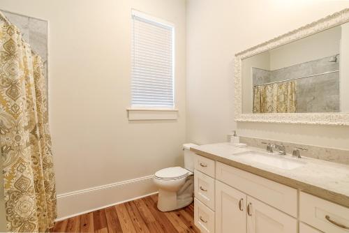 ein Badezimmer mit einem WC, einem Waschbecken und einem Spiegel in der Unterkunft Stunning 3BR on Carondelet by Hosteeva in New Orleans